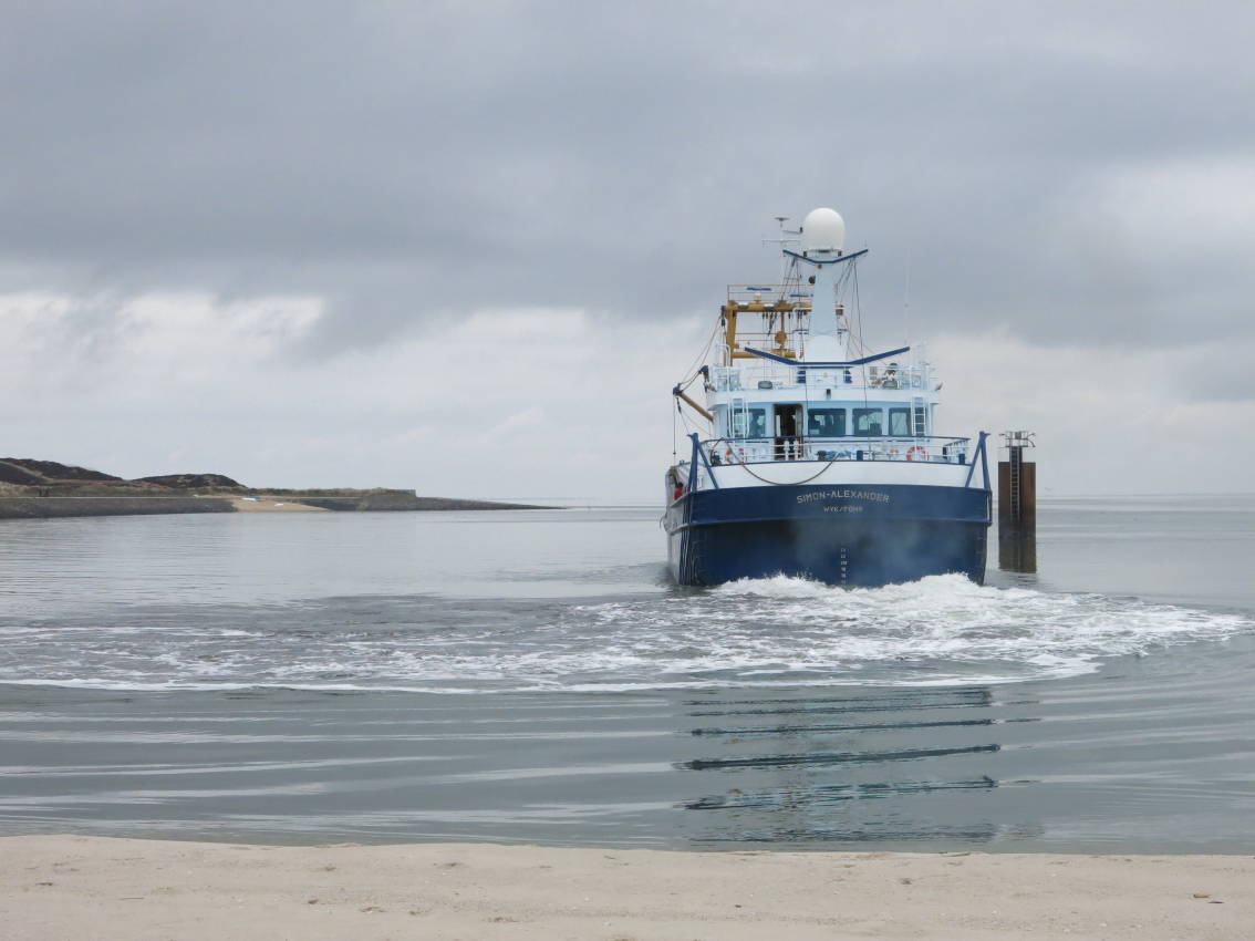 Ein Schiff startet im Hafen von Hörnum. Das Wasser erscheint trügerisch glatt.
