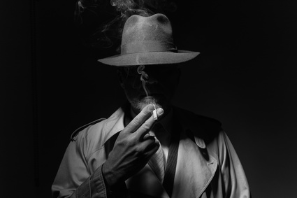 Ein Mann im Dunklen mit Hut und Zigarette