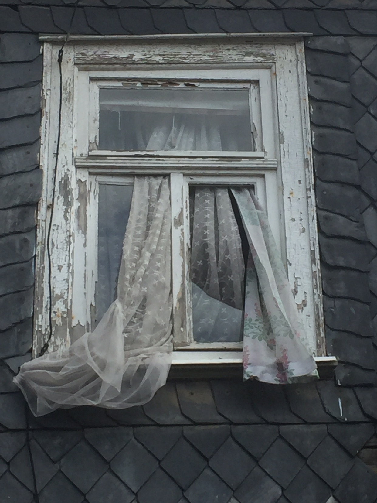 Fenster mit verschlissener Gardine