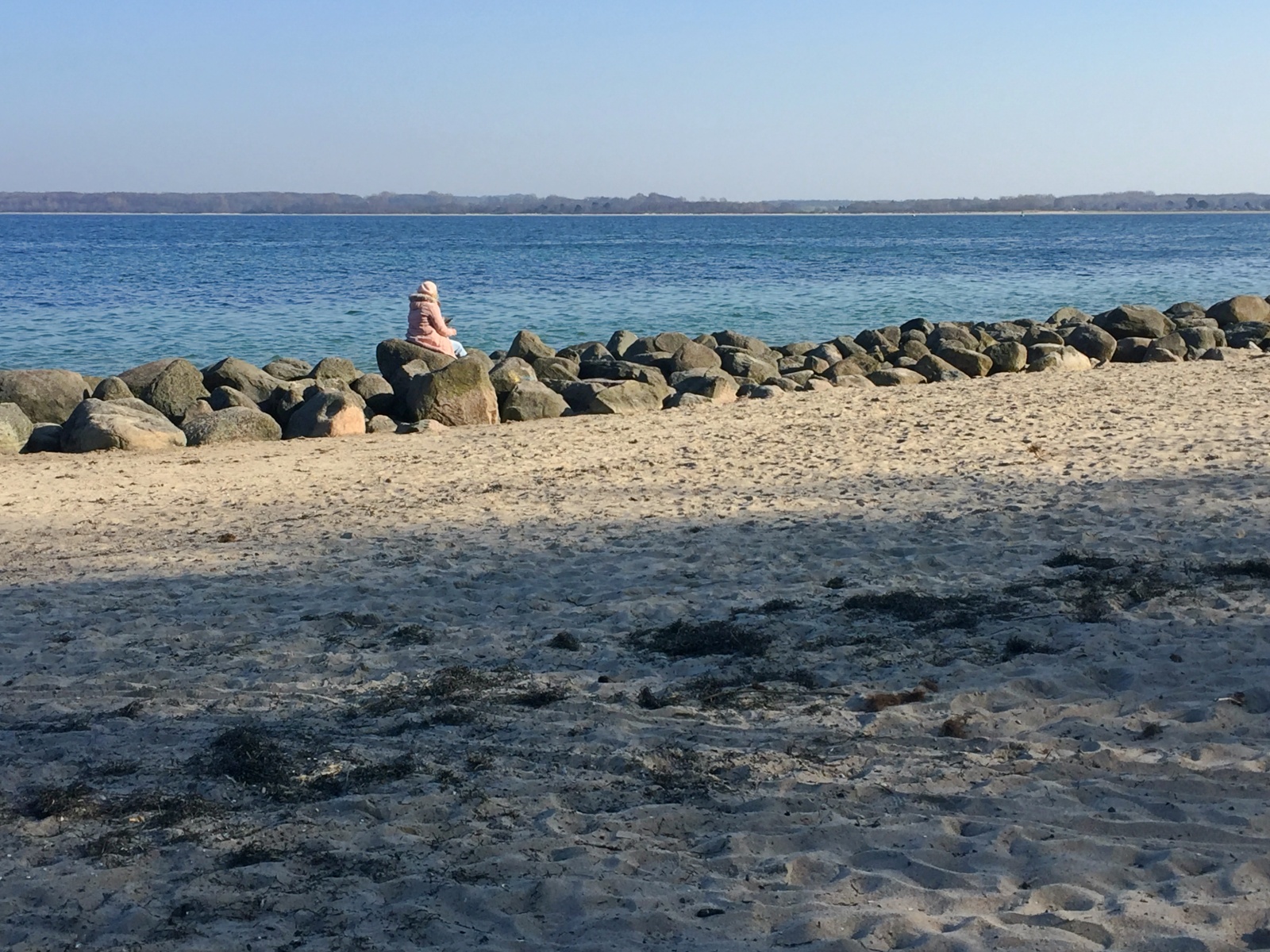 Eine Frau sitzt allein am Strand